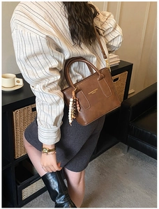 Detail of vintage brown bucket bag featuring gold hardware and beaded charm handle decoration