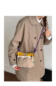 Crossbody bag detail showing multicolor patchwork design with purple braided rope strap