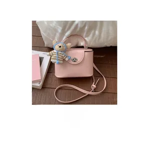 Detail of a pink leather mini handbag featuring a metal turn-lock and cute bear charm