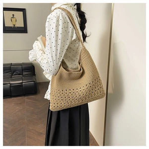 Detail of hand-woven straw tote bag with intricate crochet patterns and a large shoulder strap