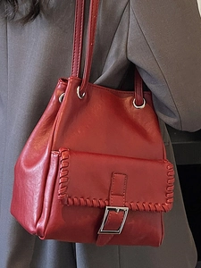 Fashionable dark red bucket bag with whipstitch detail on a grey suit model