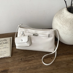 Dettaglio borsa a tracolla in pelle bianco crema con mini portamonete su superficie in legno