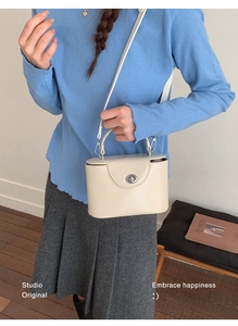 Chic cream box handbag with silver twist lock shown styled on model with pleated skirt