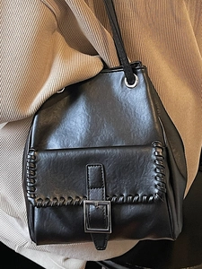 Chic black faux leather underarm bucket bag with woven stitch detail and silver buckle