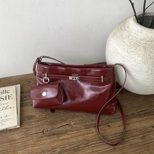 Dettaglio borsa a spalla in pelle bordeaux con chiusura a scatto in argento su legno