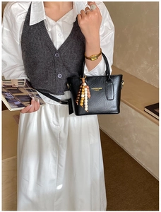 Chic black matte leather bucket bag with colorful ethnic beaded charm and top handle