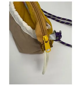 Detail of custom yellow zipper and durable nylon fabric on the color-block crossbody bag