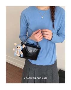 Détail du sac à main en cuir verni noir avec fermoir argenté et charm ours mignon