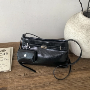 Dettaglio borsa a tracolla in pelle lucida nera con fibbia argento e mini astuccio