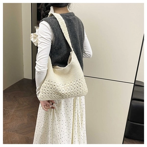 Detail of hand-woven off-white crochet tote bag with intricate floral patterns and wide strap
