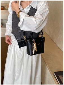 Black leather bucket bag detail with wooden bead charm and mini earphone pouch