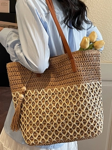 Large bohemian straw tote bag with brown leather straps and colorful tassel details