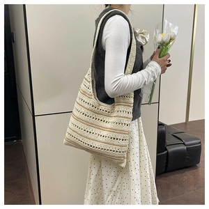 Detail view of woven tote bag with beige crochet pattern and brown stripes on shoulder
