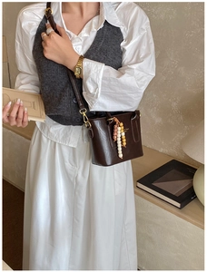 Detail of dark brown leather crossbody bag with ethnic bead tassel on a model