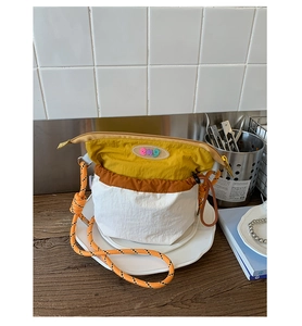 Close-up of mustard and brown nylon crossbody bag with orange woven rope strap