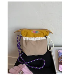 Detail of color-block nylon crossbody bag with woven rope strap and eko logo