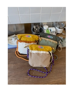Detailed view of three lightweight nylon crossbody bags with colorful woven rope shoulder straps