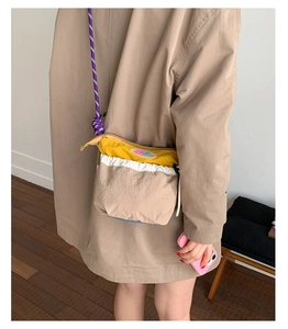 Detail view of stylish patchwork crossbody bag with purple rope strap on a model