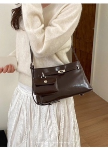 Dettaglio di una borsa tote in pelle marrone scuro con fibbia argento e mini charm su modella