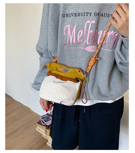 Detail of multi-color crossbody bag with orange knotted rope strap and embroidery