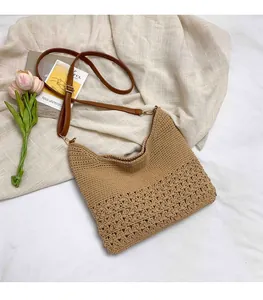 Detail of khaki woven straw bag showing hollow floral patterns and brown leather strap
