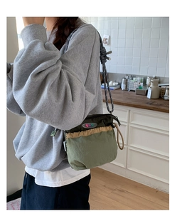 Detail of olive and khaki drawstring crossbody bag with woven rope shoulder strap