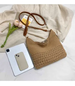 Detail of hand-woven crochet shoulder bag with hollow pattern and brown leather strap