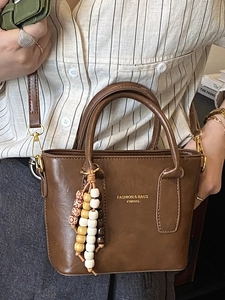 Brown PU leather bucket handbag with gold lettering and colorful wooden bead keychain charm