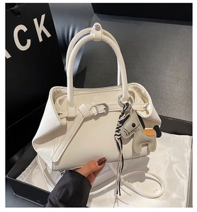 Detailed shot of white tote bag with horse charm and adjustable strap on silky fabric