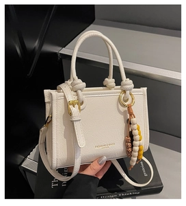 Detail view of cream wrinkled leather crossbody bag with knot handle and beads