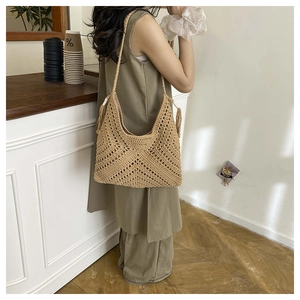 Detail einer handgehäkelten Hobo-Tasche mit Fransenquasten und böhmischer Strickstruktur