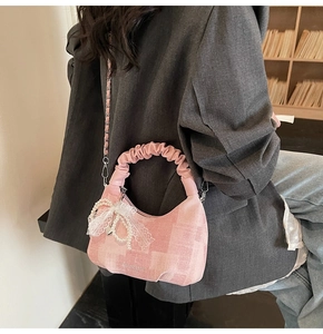 Detail of pink plaid bag with lace pearl bow charm on grey blazer model's shoulder