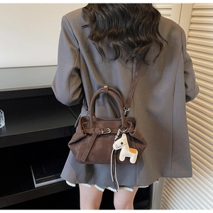 Detailed shot of dark brown matte handbag featuring a stylish horse leather charm accessory