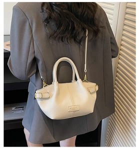 Détail du sac seau crème montrant le cuir à motif lychee et les accents dorés