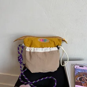 Detail of multi-color nylon crossbody bag with purple paracord strap and logo