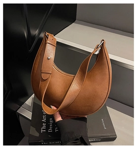Detail view of brown crescent shoulder bag with smooth leather texture and adjustable strap