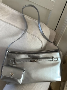 Borsa sottobraccio argento metallizzato con portamonete abbinato su divano beige
