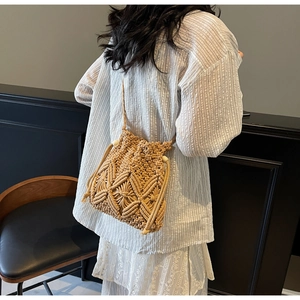 Detail of bohemian woven straw bucket bag showing complex hollow diamond patterns