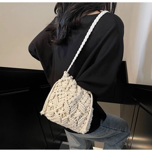 Detail showing the intricate macrame pattern and texture of a cream woven bucket bag