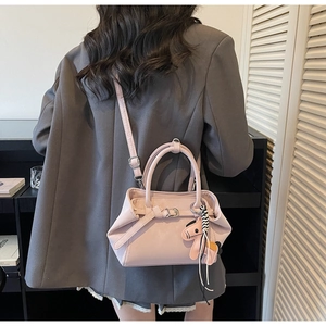 Model wearing a large pink faux leather tote bag with dog charm and crossbody strap