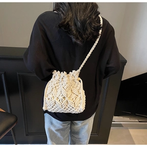 Detailed texture of white woven straw bucket bag with drawstring and braided strap