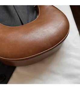 Close-up detail of smooth oil-finished edges and brown leather texture on crescent bag