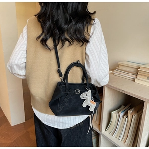 Detail of black suede shoulder bag with silver buckle and grey pony pendant