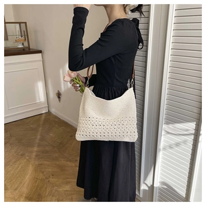 Detail of hollow woven pattern on beige straw shoulder bag with brown leather strap