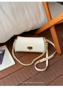 Detail of white rectangle crossbody bag with gold twist lock and woven chain strap