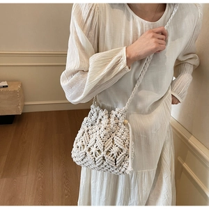 Detail of hand-woven cream bucket bag featuring hollow diamond patterns and wooden beads