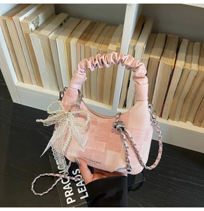 Detail of pink plaid bag with pearl bow, lace charms and pleated leather handle