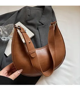 Brown leather crescent hobo bag with adjustable wide shoulder strap in lifestyle setting