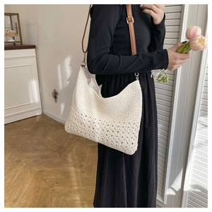 Detailed knit texture of a beige woven bag featuring intricate hollow floral patterns