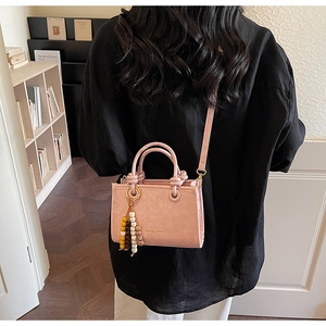 Model view showing the pink mini square bag with beads charm in a cozy indoor setting